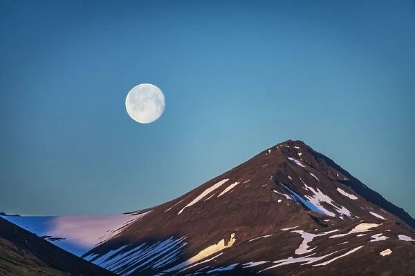 Moon over glacial mountain ridge