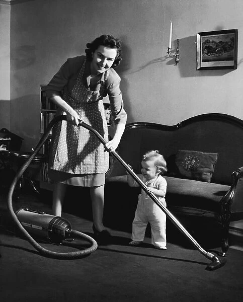 Mother and baby boy (12-15 months) holding vacuum cleaner (B&W)