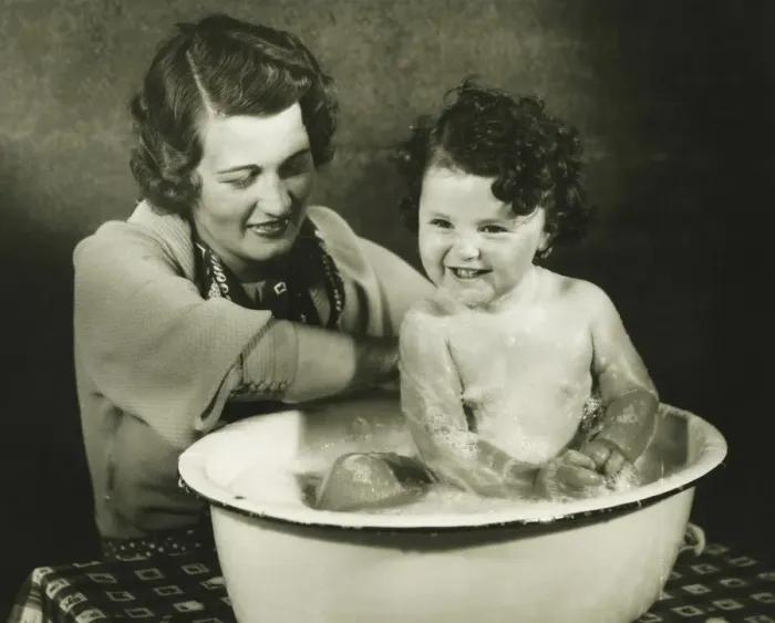 Framed Print : Mother bathing daughter (12-18 months) in basin, (B&W) Framed Print : Mother bathing daughter (12-18 months) in basin, (B&W)