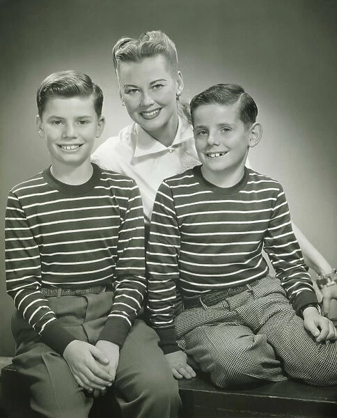 Mother with brothers (8-9) (10-11) sitting in studio, smiling, (B&W), portrait