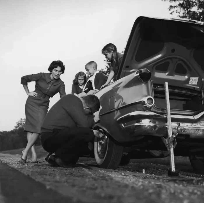 Framed Print : Mother and children (3-8) watching father change flat tire (B&W) Framed Print : Mother and children (3-8) watching father change flat tire (B&W)