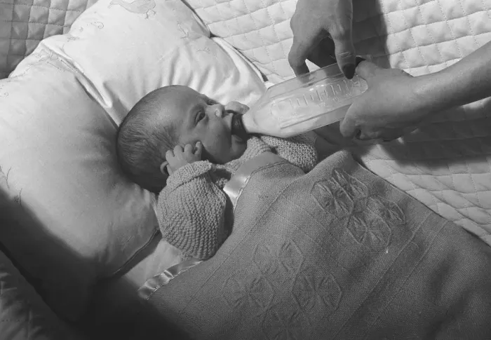 Framed Print : Mother feeding baby (0-3 months) lying in crib with baby bottle, (B&W), close-up Framed Print : Mother feeding baby (0-3 months) lying in crib with baby bottle, (B&W), close-up