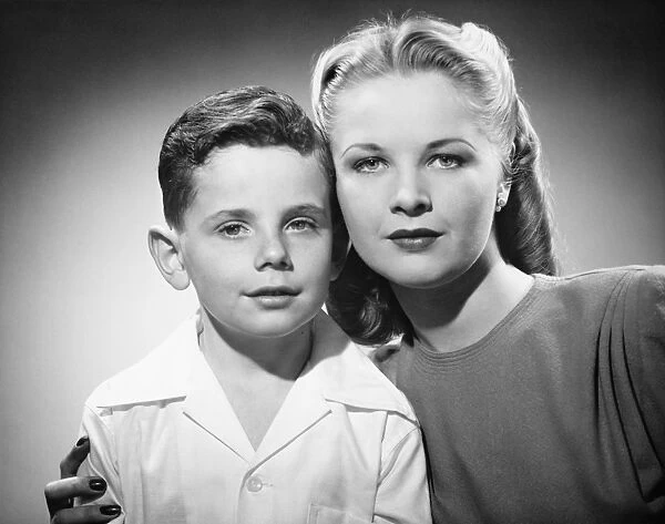 Mother with son (6-7) posing in studio, (B&W), portrait