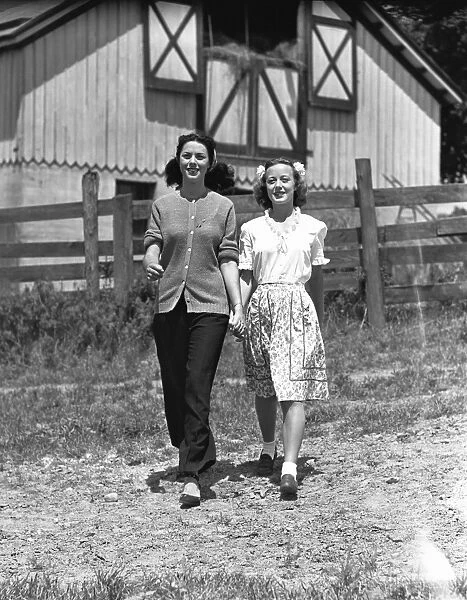 Mother with teenage daughter(13-14) walking on field in front of barn