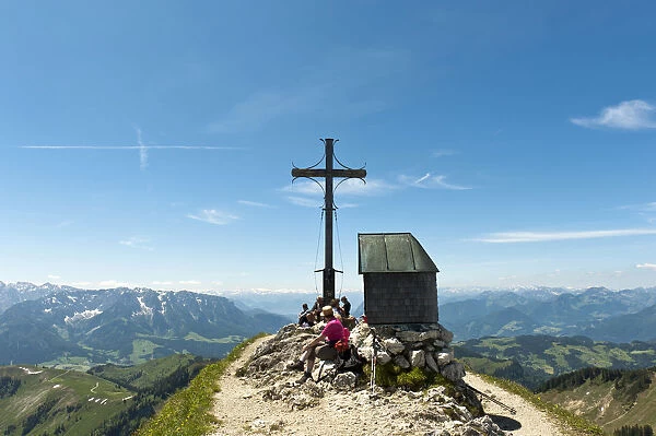 Mountain climber at the summit cross with a small chapel on Geigelstein Mountain, 1808 m, Geigelstein Nature Reserve, Aschau im Chiemgau, Upper Bavaria, Bavaria, Germany