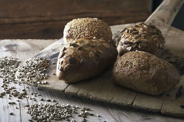 Multigrain bread rolls on old bread slide with rye grains
