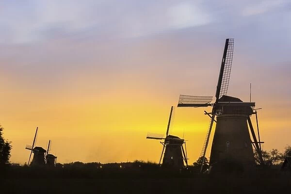 Netherlands, South Holland, Kinderdijk, Winmills silhouetted against sunset sky