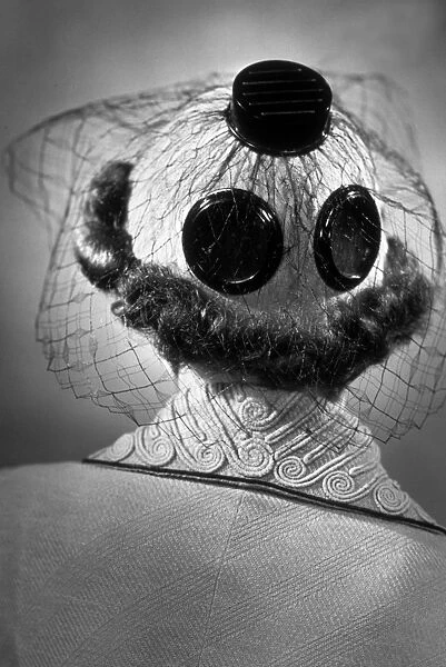 A New Hat. 15th March 1937: The back view of a hat decorated with large buttons and net,
