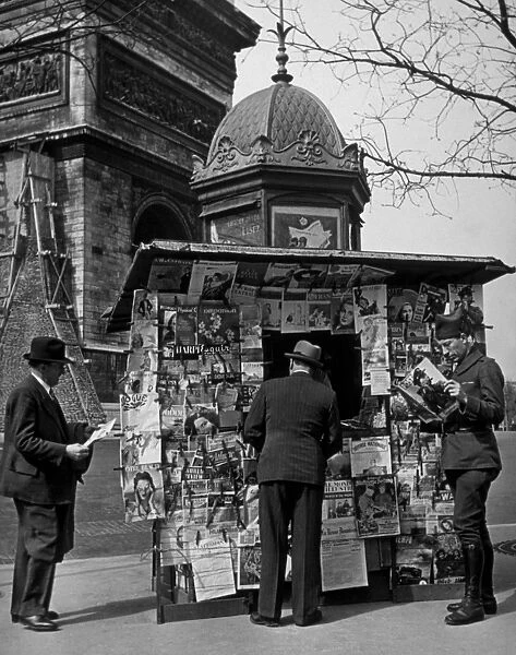 Newsstand. A soldier in Paris reading Picture Post at a newstand