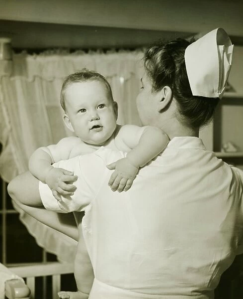 Nurse holding baby boy (6-12 months), (B&W)