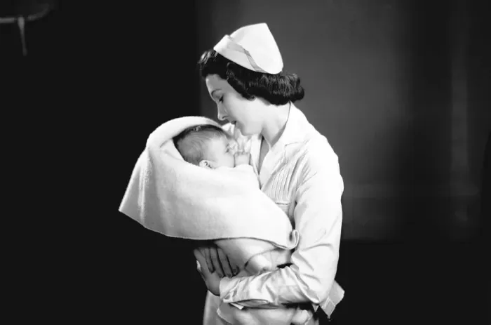 Framed Print : Nurse hugging newborn (0-3 months) wrapped in blanket, (B&W) Framed Print : Nurse hugging newborn (0-3 months) wrapped in blanket, (B&W)