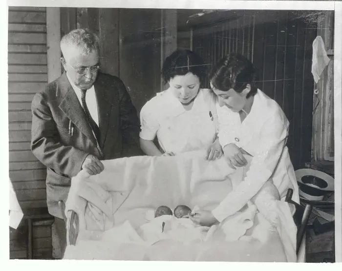 Framed Print : Nurses and Doctor Viewing Infants Lying Together Framed Print : Nurses and Doctor Viewing Infants Lying Together