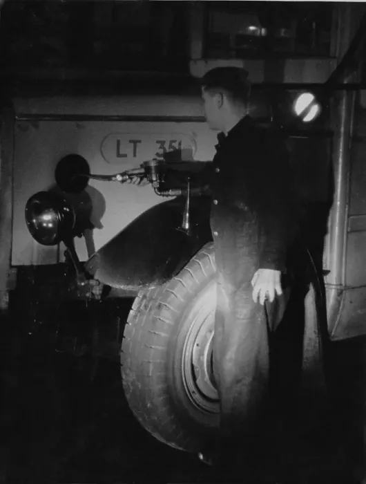Framed Print : Oil Fill. A maintenance worker at a London bus garage tops up the oil on
