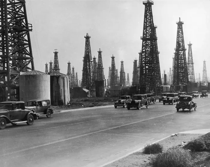 Framed Print : Oil Field. circa 1930: Derricks stand behind traffic on a highway at the Framed Print : Oil Field. circa 1930: Derricks stand behind traffic on a highway at the