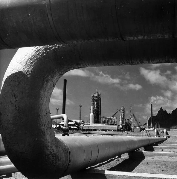 Oil Pipe. 29th April 1958: A section of pipe frames the crude oil distillation