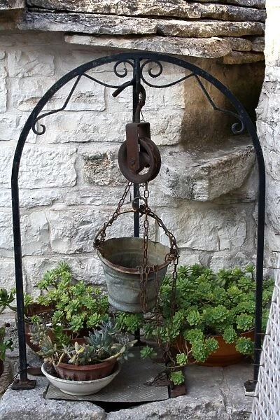 Old well and metal bucket near a Trullo house in Alberobello, near Bari, Apulia, southern Italy