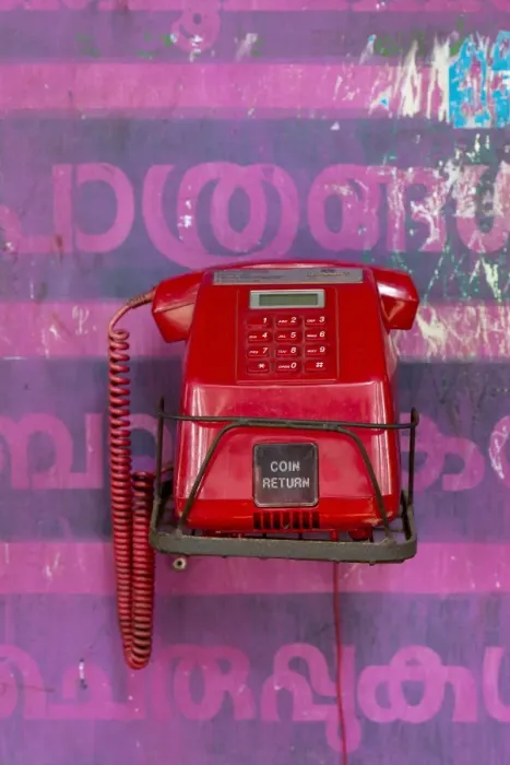 Framed Print : Old red telephone against a wall with pink Malayalam script, Kerala, India Framed Print : Old red telephone against a wall with pink Malayalam script, Kerala, India