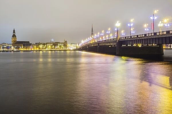 Old Riga skyline at night and Akmens bridge over Daugava river. Riga, Latvia