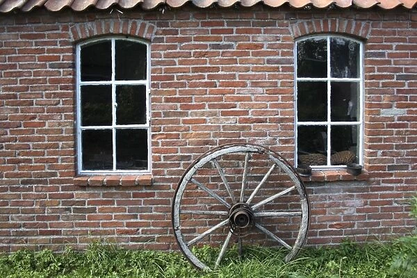 Old wagon wheel on a facade, brick stone, East Frisia, Lower Saxony, Germany, Europe