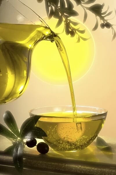 Olive oil flowing from a glass jug in a glass bowl