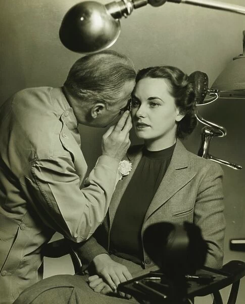 Optician examining womans eye, (B&W)