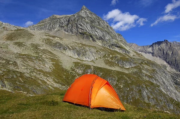 Orange-coloured mountain tent below the summit of Wiwanni Mountain in the Pennine Alps, Valais, Switzerland, Europe