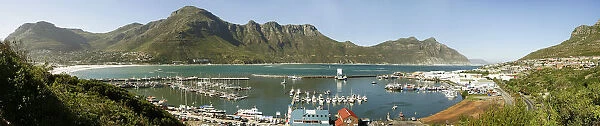 A panoramic picture of Hout Bay with Hout Bay Beach on the left and the marina and fishing harbour in the foreground. Chapmans Peak is in the background. Western Cape Province, South Africa