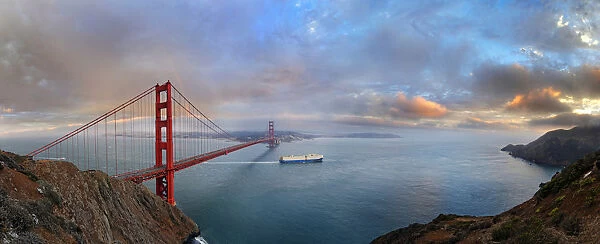 Panoramic view of the Golden Gate Bridge at sunset with a rainbow and storm clouds, San Francisco, California, United States
