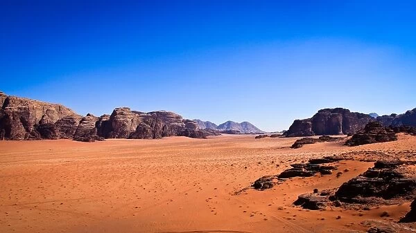 Panoramic view of Wadi Rum with clear blue sky background and some rock boulders