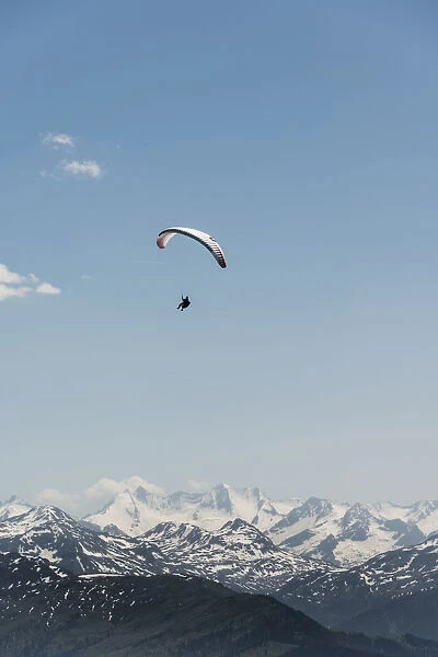 Paraglider against a blue sky, snow-capped peaks of the Alps at the back