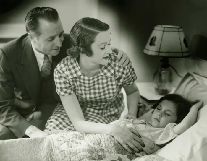 Framed Print : Parents looking at sleeping daughter (6-7), (B&W) Framed Print : Parents looking at sleeping daughter (6-7), (B&W)