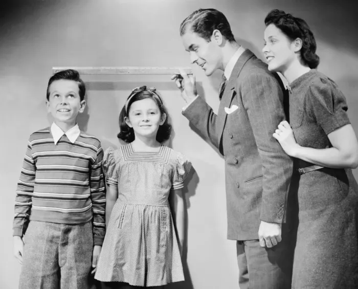 Framed Print : Parents measuring children standing against wall, boy (8-9) girl (6-7), (B&W) Framed Print : Parents measuring children standing against wall, boy (8-9) girl (6-7), (B&W)