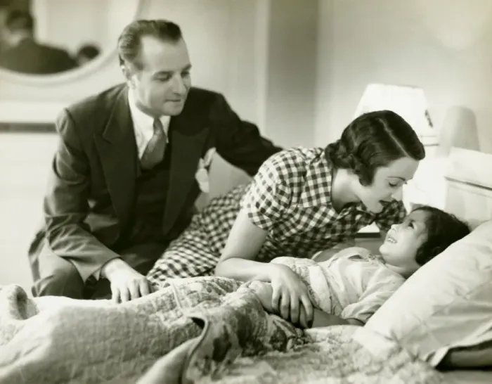 Framed Print : Parents tucking daughter (6-7) into bed, (B&W)