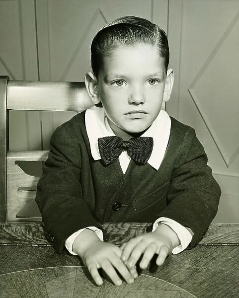 Pensive boy (4-5) posing at table, (B&W), portrait