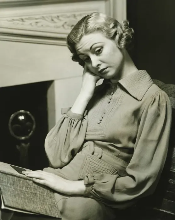 Framed Print : Pensive woman sitting by fireplace with book on laps, (B&W) Framed Print : Pensive woman sitting by fireplace with book on laps, (B&W)