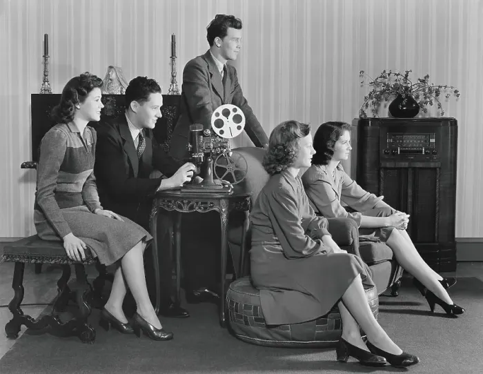 Framed Print : Five people watching home movies, seated around projector, looking toward screen