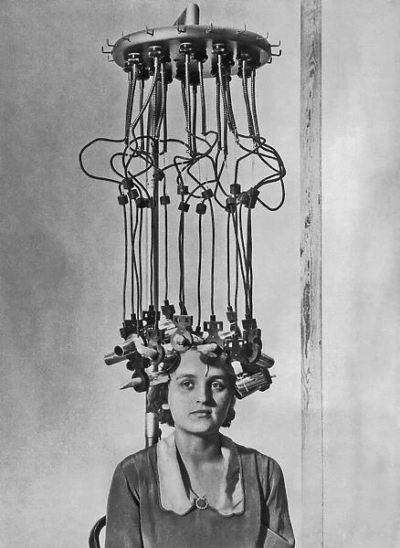 Perm Machine. A model having her hair permed by a permanent wave machine