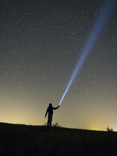 Person lighting the sky with a flashlight