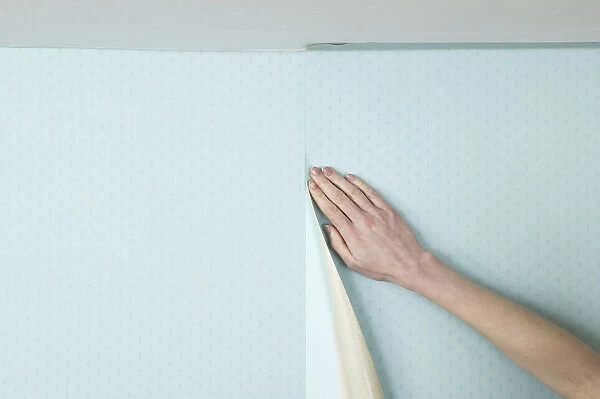 Person smoothing wall paper onto a wall