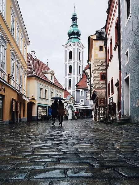 Two persons with one umbrella wandering in the cobbled streets in the old town of Cesky Krumlov, South Bohemia, Czech Republic