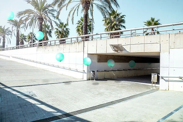 Poetic stop motion picture of green balloons following each other going out from tunnel in a minimal and cool underground pass in the city