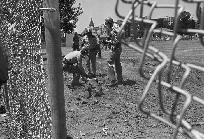 Framed Print : Police Drag Protester, View Through Fence