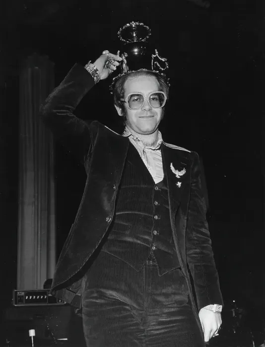 Framed Print : Crunk. CIRCA 1975: Pop singer Elton John holds up a fancy cup wearing a corduroy suit Framed Print : Crunk. CIRCA 1975: Pop singer Elton John holds up a fancy cup wearing a corduroy suit