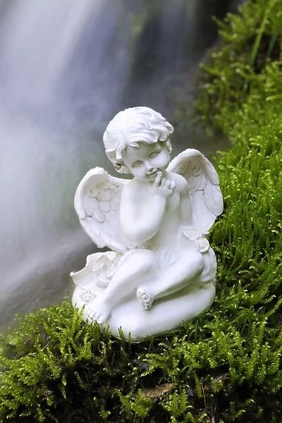 Porcelain angel figure on moss at a waterfall