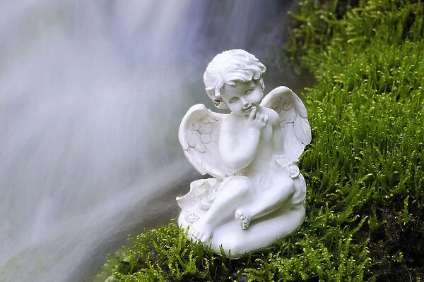 Porcelain angel figure on moss at a waterfall