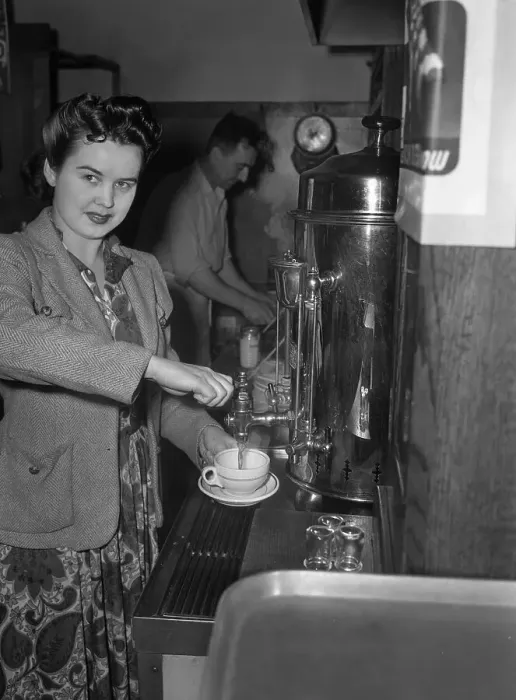 Framed Print : Portrait of young woman using coffee machine, man in background