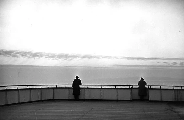 QE2 Liner. 1952: Two men lean on the rails on deck of the Queen Elizabeth