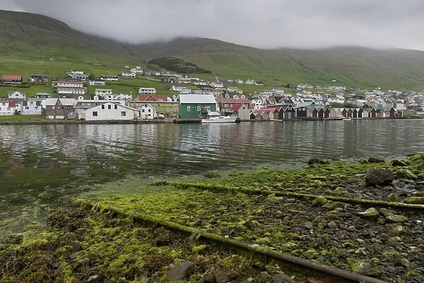 Rails on a boat ramp, covered in algae, boathouses at the back, Vagar, Faroe Islands, Denmark