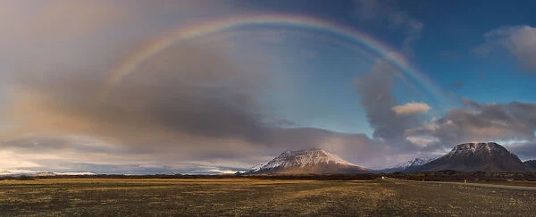 Rainbow arch over grass field in Iceland