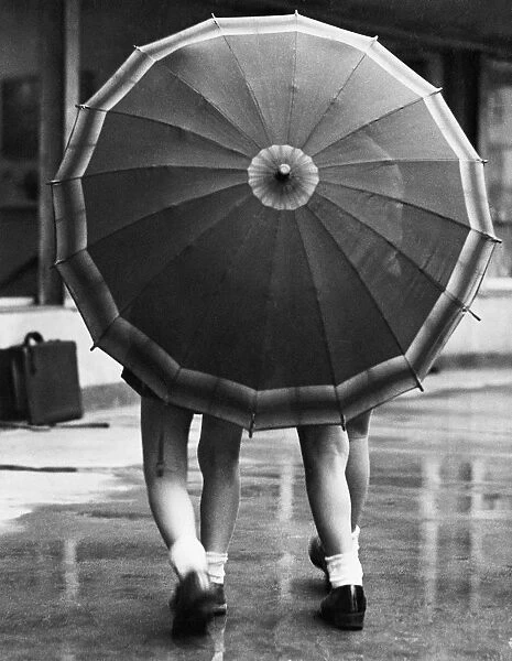 Rainy Day. 31st December 1938: Two little girls share an umbrella during a shower of rain